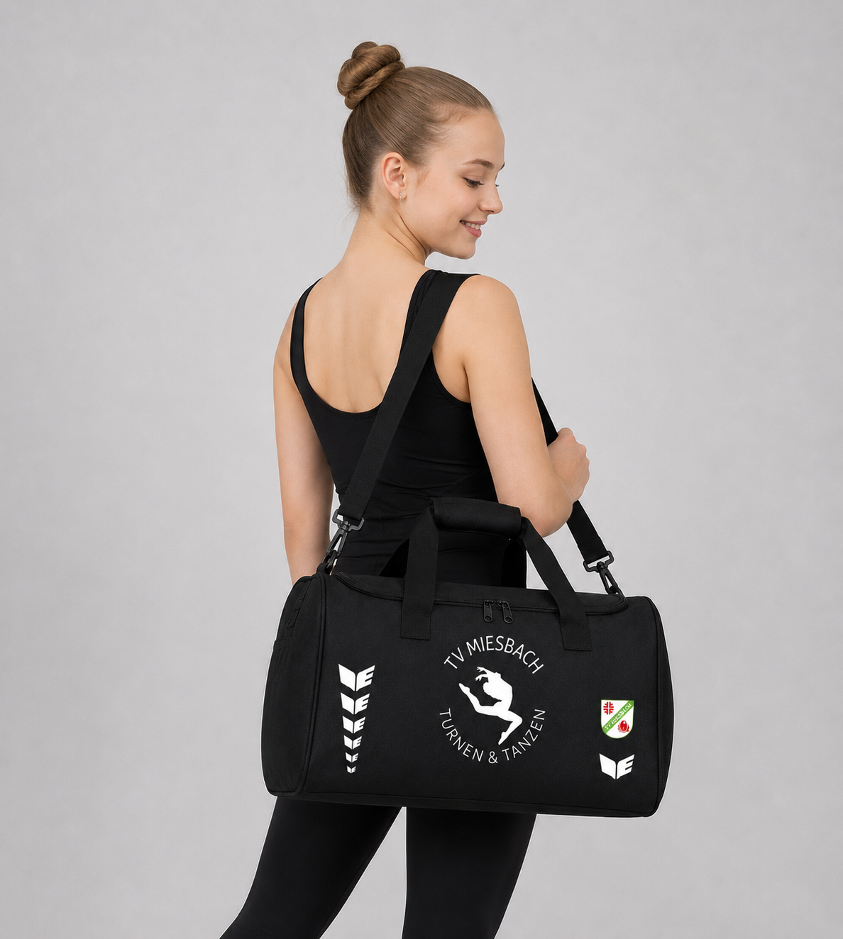 Frau die eine schwarze bedruckte Sporttasche von Erima trägt